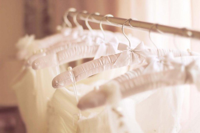 Beautiful white cream wedding dresses made of silk chiffon, tulle and lace hanging on hangers with bows